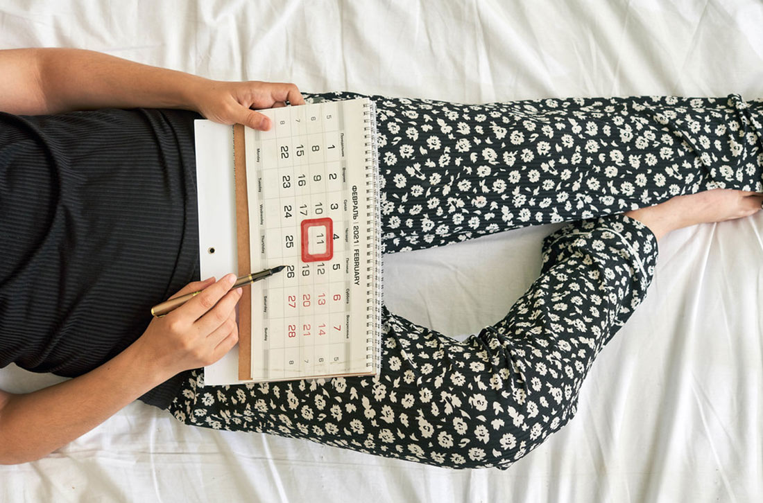 femme allongée avec un calendrier menstruel